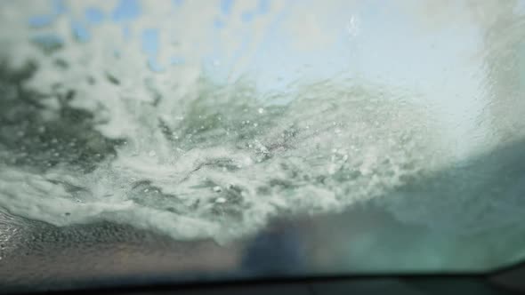 Closeup Water Spraying on Automobile Windshield in Slow Motion