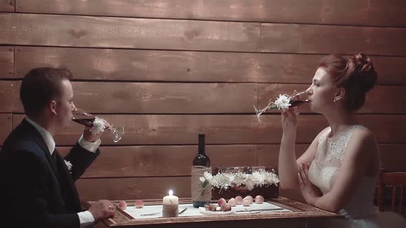 Young Couple Sitting in Restaurant at Table and Drinking Wine