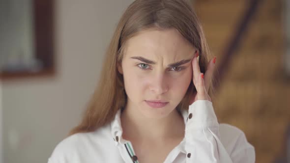 Portrait of Confident Carefree Cute Woman with Different Colored Eyes Looking at Camera Indoors