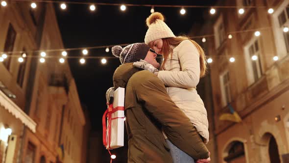 Smiling Couple Celebrating Xmas Eve Together at Bright Garland Decoration