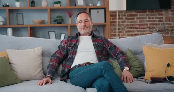 Portrait of Relaxed Middle Eastern Man Looking at Camera Sitting on couch.