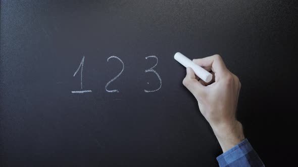 Education concept. Hand holding chalk and writing 12345 numbers on chalkboard