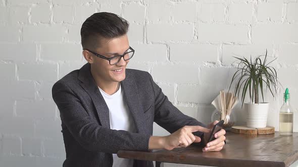 Young Man Using Mobile Phone at Cozy Coffee Shop.