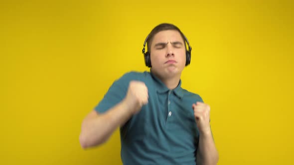 Young Man Dancing with Headphones on a Yellow Background. A Man in a Green Polo Is Listening To