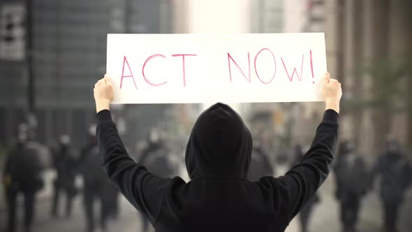 Unknown Protester Holds a Placard with ACT NOW Text