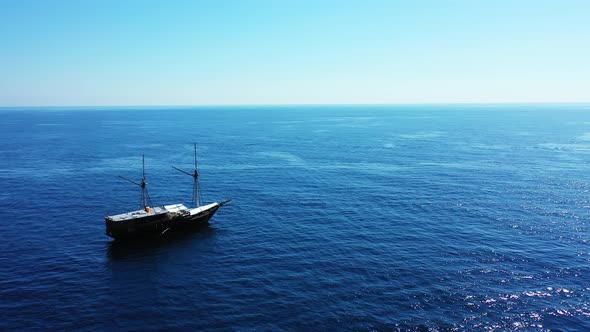 A large white and black ship alone in the middle of the beautiful blue waters of the ocean