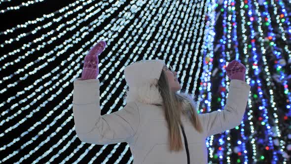 A Young Girl Admires the New Year's Decorations of the Night Christmas City