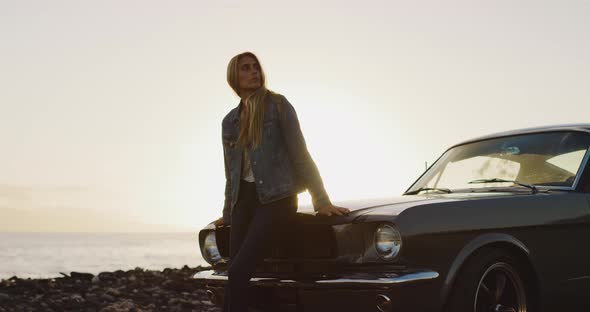 Beautiful woman sitting on the hood of a vintage car