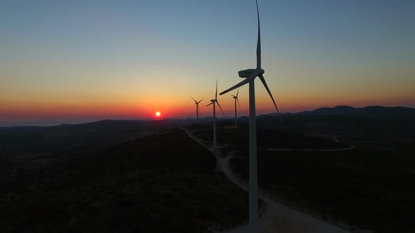 Aerial view of windmills with slowly rotating blades at sunset