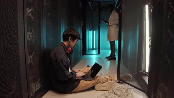 Two IT Specialists Coding on Laptops in Server Room
