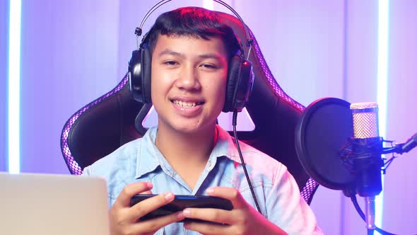 Asian Kid Boy Playing Video Game With Mobile Phone Then Smiles To Camera While Live Stream