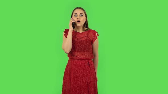 Tender Girl in Red Dress Is Talking for Mobile and Shocked Then Rejoice. Green Screen