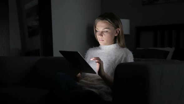 Woman Reacting to Success While Using Tablet at Night