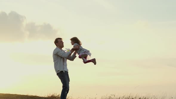 Family Vacation In Nature. Dad Twists His Daughter In His Arms As If She Were Flying.