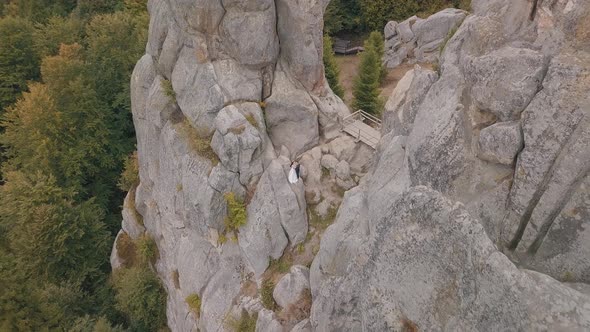 Newlyweds Stand on a High Slope of the Mountain. Groom and Bride. Aerial View