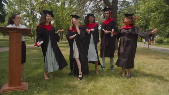 Carefree Diverse Multiethnic Graduates with Diploma Dancing on Green Lawn
