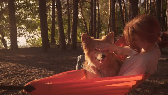 Girl Lying In The Hammock With Her Fluffy Corgi Dog 2