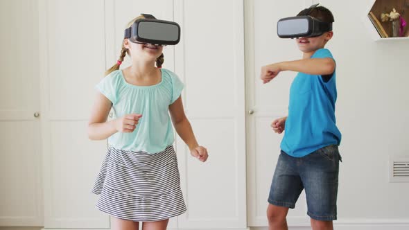 Caucasian brother and sister gesturing while wearing vr headset at home