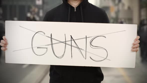 Unknown Rioter Holds a Placard with NO GUNS Text