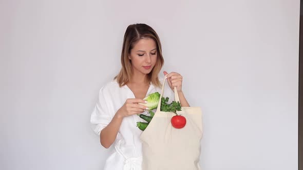 woman in white clothes showing bag with different vegetables