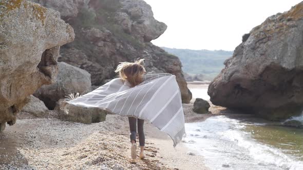 Beautiful Young Woman with Long Blond Hair Runs Away Against the Backdrop of a Stunning Sea View in