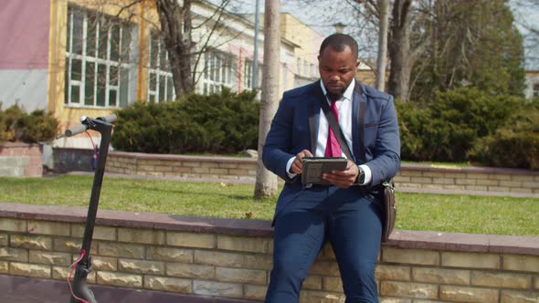 Black Businessman Networking on Tablet Pc in Public Park