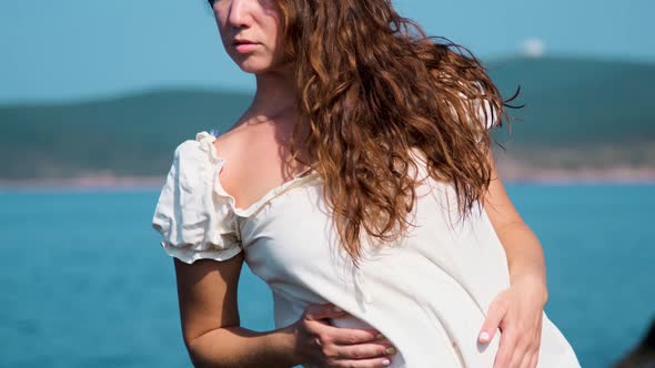 girl in a white sundress on the background of the sea on a bright sunny day