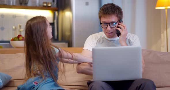 Little Child Girl Distracting Father From Work Sitting on Couch at Home