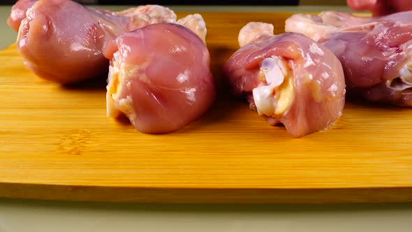 Fresh chicken legs are laid out on a cutting board.