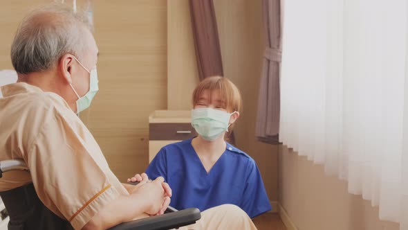 Asian beautiful nurse taking care of senior mature older male patient sit on wheelchair in hospital.