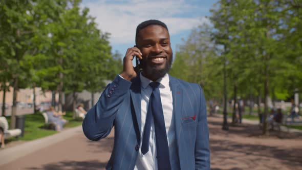 Close Up of Afro-american Businessman Talking on Smartphone Walking in Park