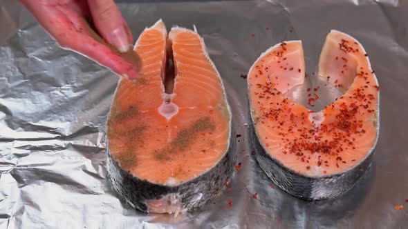 Seasoning salmon steak. Chef adding spices on raw salmon steak before baking. Raw salmon Fillet