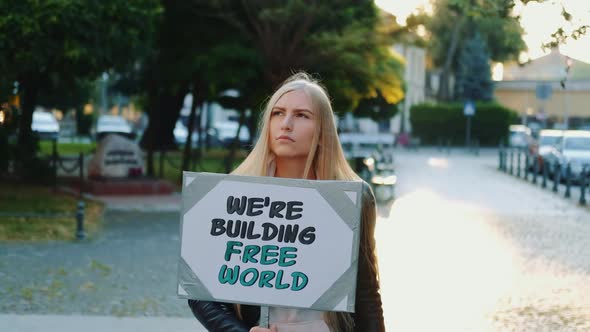 Blonde Woman Holding Streamer with Slogan "Building Free World"