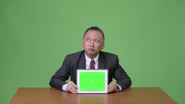 Mature Japanese Businessman Showing Digital Tablet