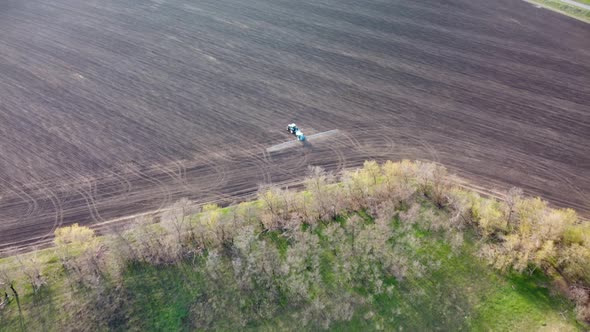 Aerial tractor turning and spraying on land field