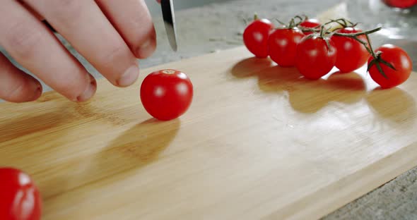 The Chef Cuts Tomatoes with a Knife on a Wooden Surface. Close Up