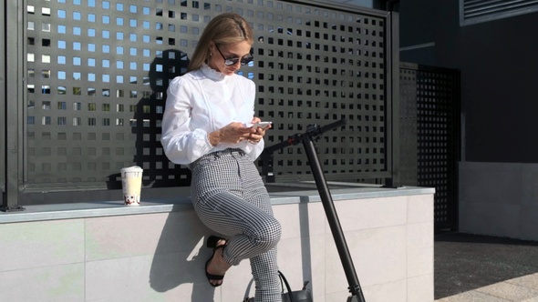 Businesswoman with mobile and her scooter next