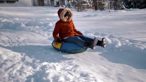 Funny Warmly Dressed Woman Is Rolling Down a Hill on an Inflatable Snowtube