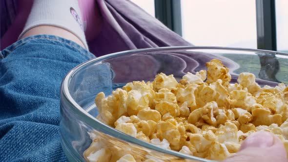 An Unrecognizable Person Lies in a Hammock Resting and Eating a Snack Caramel Popcorn