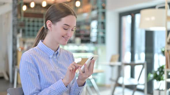 Young Businesswoman Using Smartphone in Cafe