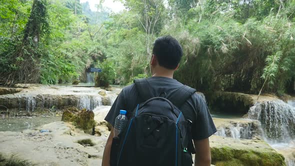 Man Walking Near Waterfall