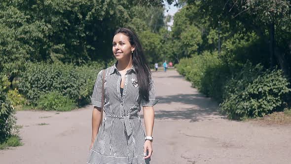 Pretty Young Woman in Summer Dress Walks Along Park Alley