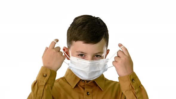 Little Boy Taking His Face Mask Off and Smiling at Camera on White Background.