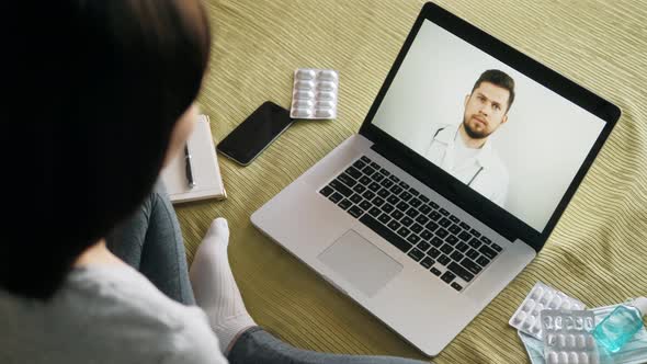 Back View of Woman Making Video Call with Her Doctor While Staying at Home During Coronavirus