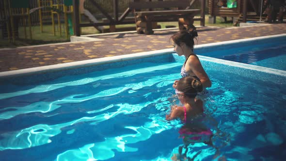 Elder Sister in Leopard Swimsuit Pulls Little Sister Out of the Pool with Blue Water