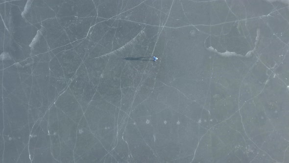 one person on a frozen lake ice-skating. drone shot