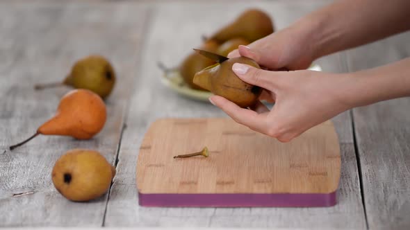 Woman Peeling Pear for Dessert Over Table.