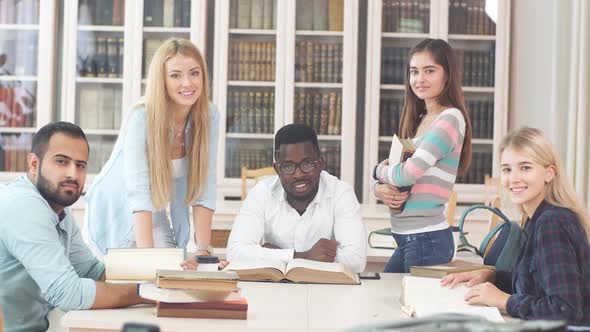 Multiracial Students Having Fun in Library While Preparing for Exams