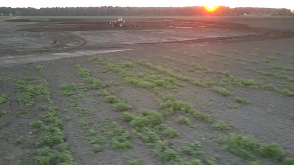 Wide Field and Cultivator Plowing Soil at Dusk Bird Eye View