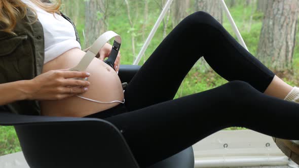 close-up of a pregnant woman holding headphones on her stomach